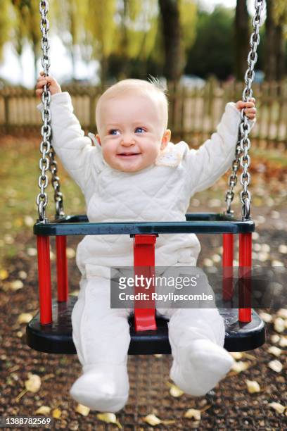 cute 12 month old baby girl laughing and smiling as she enjoys her first swing - baby swing stock pictures, royalty-free photos & images