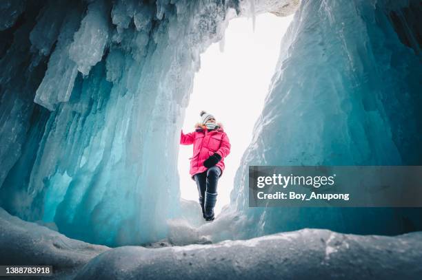 young asian woman visiting an ice cave in lake baikal of russia during winter season. - aushöhlung stock-fotos und bilder