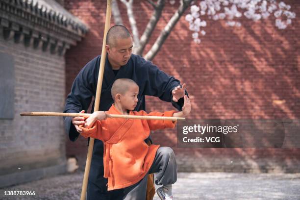 Monk and a child practice Kung Fu underneath blooming cherry blossoms at Shaolin Temple on March 30, 2022 in Dengfeng, Zhengzhou City, Henan Province...