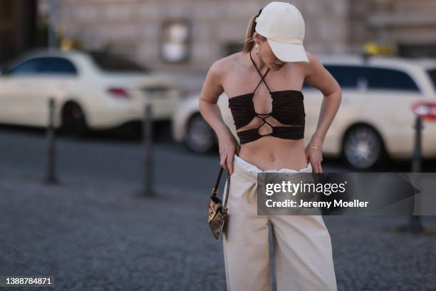 Sophia Geiss seen wearing a brown crop top from LeGer, a white LeGer cap, a beige wide leg denim jeans from LeGer and a brown vintage Fendi Baguette...