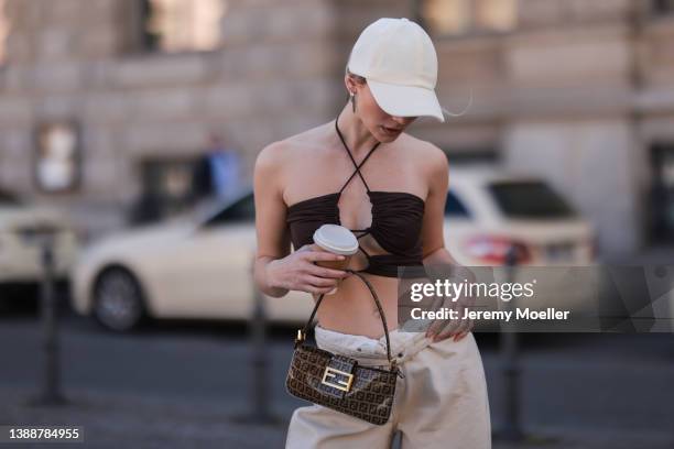 Sophia Geiss seen wearing a brown crop top from LeGer, a white LeGer cap, a beige wide leg denim jeans from LeGer and a brown vintage Fendi Baguette...