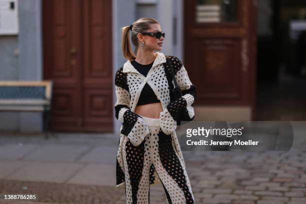 Sophia Geiss seen wearing a black Prada sunglasses, a black crop top from LeGer, a black and white striped crochet cardigan from LeGer, matching...