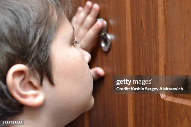 a teenage boy looking through peephole. - peephole bildbanksfoton och bilder