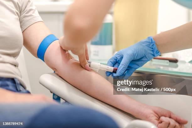 close-up of doctor taking blood sample from patients arm in hospital - hormone stock-fotos und bilder