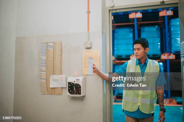 asian chinese blue collar worker clock in with time card punching in the morning - klaassen bildbanksfoton och bilder