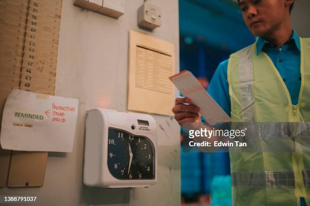 asian chinese blue collar worker clock in with time card punching in the morning - punching clock stock pictures, royalty-free photos & images
