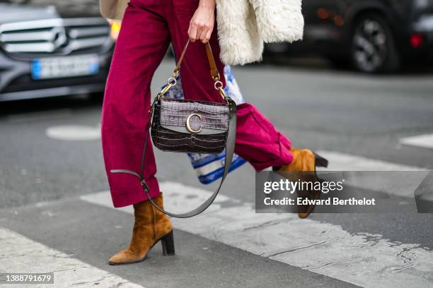 Guest wears brown a burgundy red ribbed velvet / zipper neck /large jumpsuit, a white fluffy oversized coat, a black varnished leather crocodile...