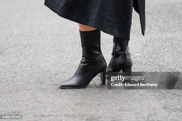 Guest wears a black long coat, black shiny leather block heels ankle boots , outside Gauchere, during Paris Fashion Week - Womenswear F/W 2022-2023,...