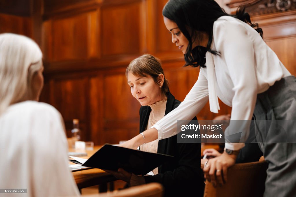 Female financial advisors brainstorming over document at table in office