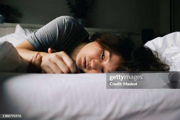 tired woman suffering from mental health disorder lying on bed alone at home - acostado de lado fotografías e imágenes de stock