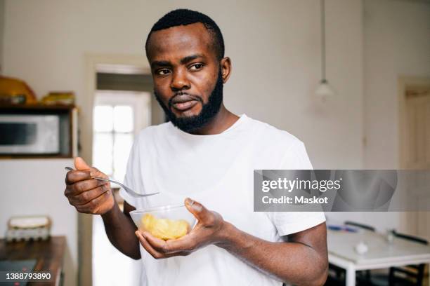 thoughtful man looking away while eating alone at home - stress eating stock pictures, royalty-free photos & images