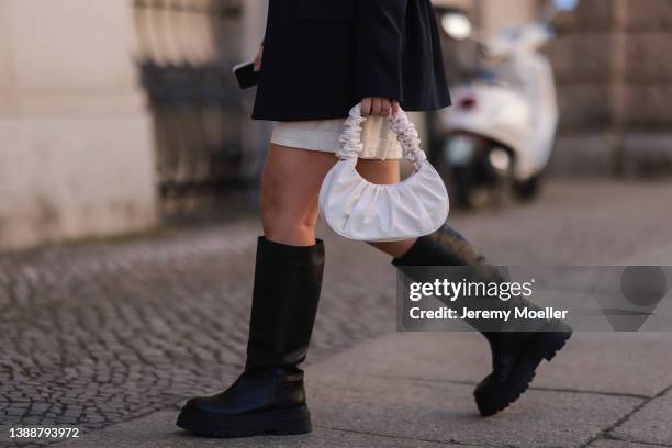 Bella Emar seen wearing a black oversize LeGer blazer, a creme linen shorts from LeGer, a white leather handbag and black leather high boots from...