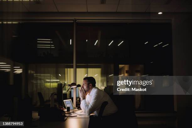 businessman concentrating while working overtime in office at night - one man only business stock pictures, royalty-free photos & images