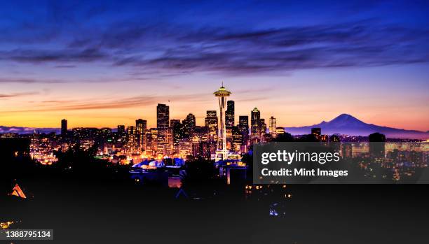 mount rainer seen behind modern seattle skyline in a colourful winter dawn. - seattle winter stock pictures, royalty-free photos & images