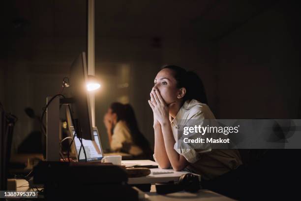 businesswoman with hands covering mouth working on computer in office - work stress stockfoto's en -beelden