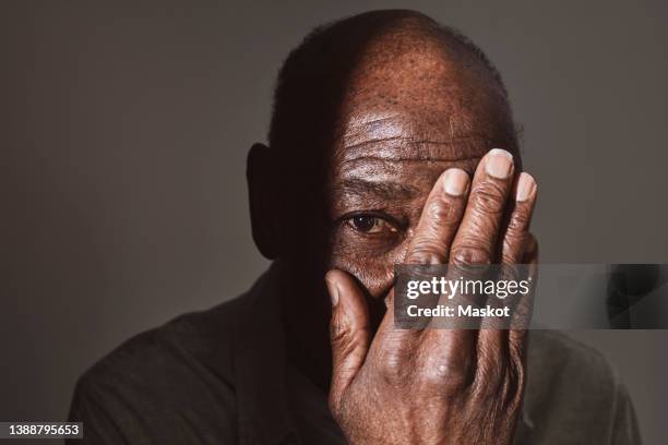 elderly man covering eye with hand at studio - touching eyes stock pictures, royalty-free photos & images