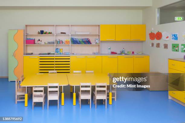 classroom in a kindergarten school, yellow furniture and tables and blue floor. - daycare stock pictures, royalty-free photos & images