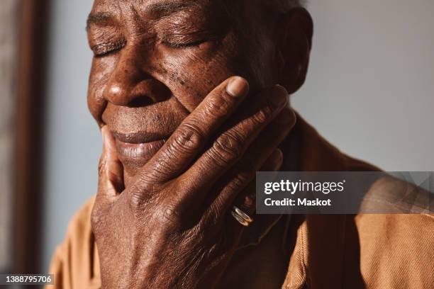 elderly man with hand on chin against wall - touching face stock pictures, royalty-free photos & images