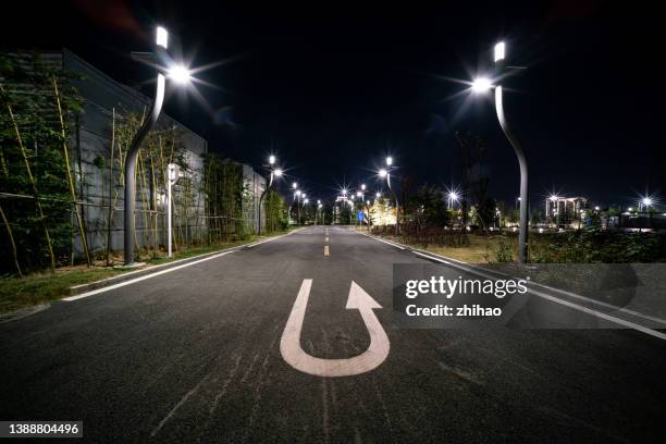 vehicle u-turn symbol on asphalt road in city street at night - drehen stock-fotos und bilder