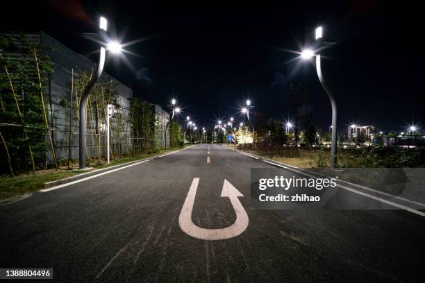 vehicle u-turn symbol on asphalt road in city street at night - turning stock pictures, royalty-free photos & images