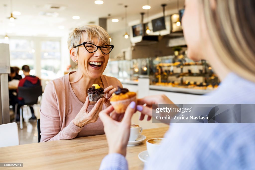 Donne sorridenti che parlano davanti a cupcake e caffè