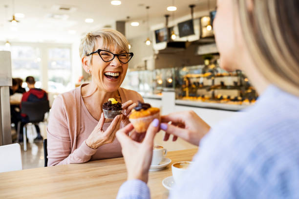 smiling women talking over cupcake and coffee - dessert cafe stock pictures, royalty-free photos & images
