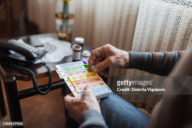 älterer mann, der medikamente in einen pillen-organizer gibt, nahaufnahme - ageing population stock-fotos und bilder