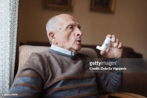 old man having respiratory system issues and using an inhaler - respiratory disease stock pictures, royalty-free photos & images