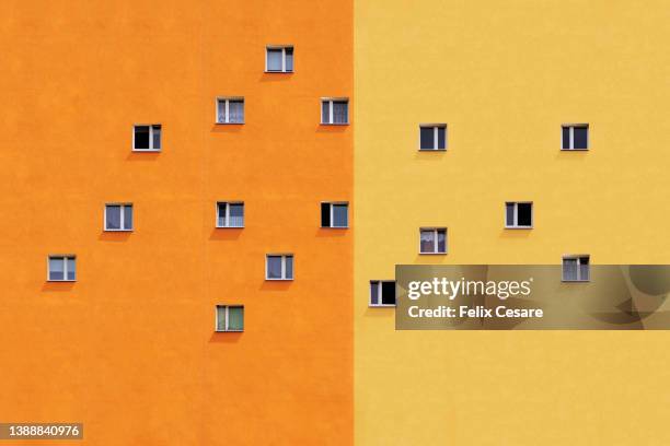 an abstract background of apartment windows against an orange and a yellow wall. - two tone stock pictures, royalty-free photos & images