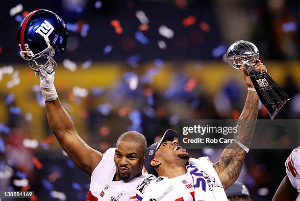 Osi Umenyiora and Devin Thomas of the New York Giants celebrate with the Vince Lombardi trophy after the Giants won 21-17 against the New England...
