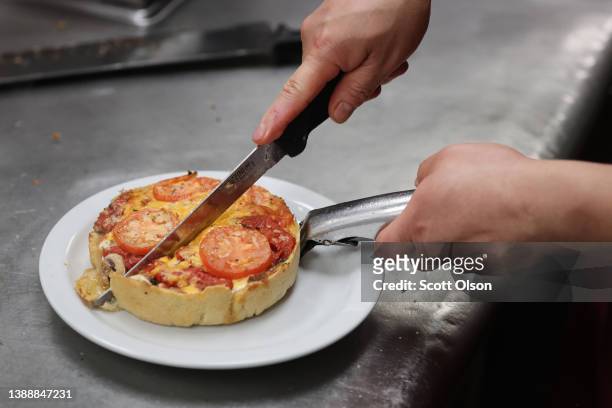 Worker prepares a Chicago-style deep dish pizza at a Lou Malnati's restaurant on March 31, 2022 in Chicago, Illinois. Restaurants, like the...