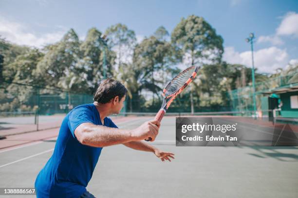 asiatisch-indischer tennistrainer zielt darauf ab, auf dem tennisplatz richtig zu posieren - bildtechnik stock-fotos und bilder