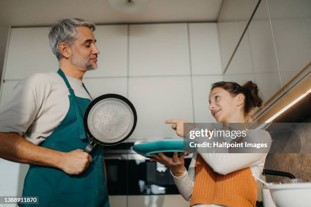 teenage girl with her father cooking in kitchen together. - fathers day lunch stock pictures, royalty-free photos & images