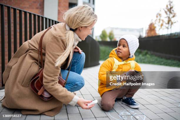mother with little child drawing on sidewalk with chalks on autumn day. - family chalk drawing stock pictures, royalty-free photos & images
