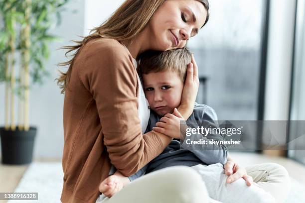 loving mother consoling her sad son at home. - sad mum stock pictures, royalty-free photos & images