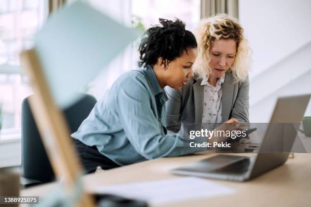 zwei unterschiedliche geschäftsfrauen arbeiten gemeinsam im büro - versicherungsvertreter stock-fotos und bilder