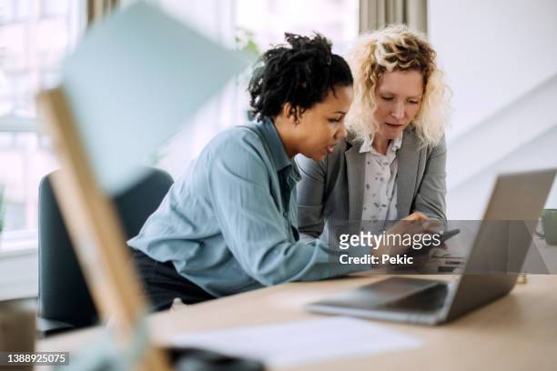 two diverse businesswoman working together in office - financieel adviseur stockfoto's en -beelden