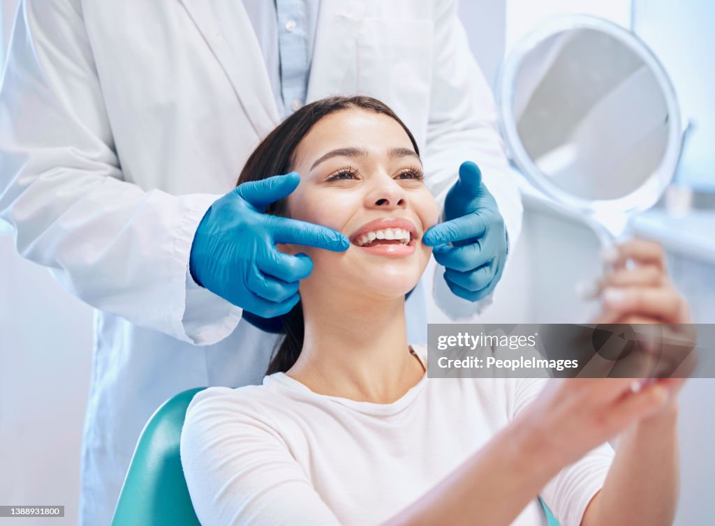 Shot of a young woman checking her results in the dentists office