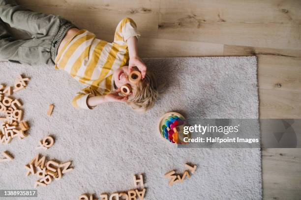 top view of little boy lying on rug and playing at home. - child playing stock-fotos und bilder