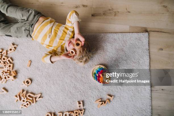 top view of little boy lying on rug and playing at home. - speels stockfoto's en -beelden