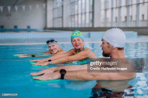 coach teaching senior woman and man to swim in swimming pool. - aqua aerobics stockfoto's en -beelden