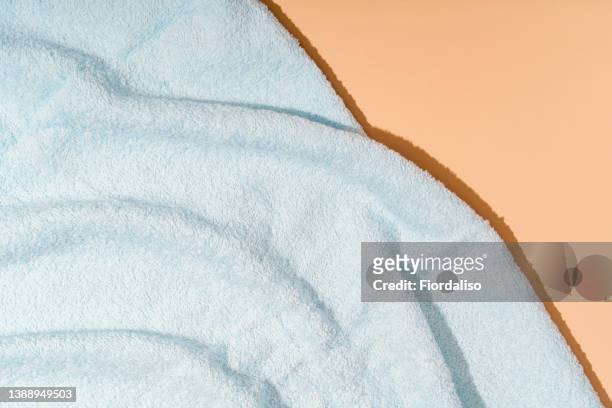 blue towel lying on the coastal sea pebbles - folded towel stock-fotos und bilder