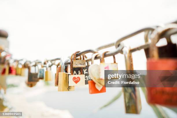 multi-colored padlocks with signed names and dates. the tradition of hanging a lock as a keepsake during a wedding or engagement - innamorarsi foto e immagini stock