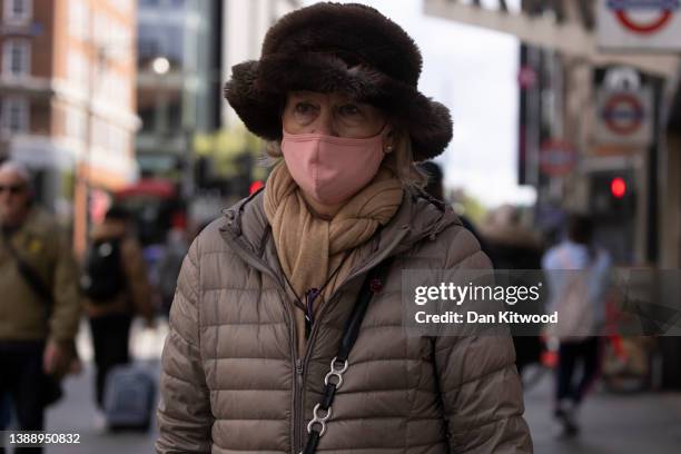 Woman wears a face mask while walking on Oxford Street on April 01, 2022 in London, England. From today, guidance on voluntary COVID-status...