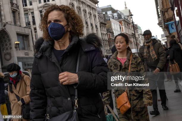 Woman wears a face mask while walking on Oxford Street on April 01, 2022 in London, England. From today, guidance on voluntary COVID-status...