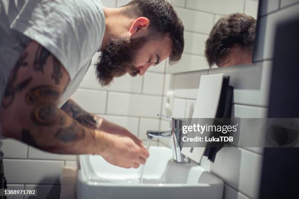 eine seitenansicht eines bärtigen mannes, der sich das gesicht wäscht. - hands fountain water stock-fotos und bilder