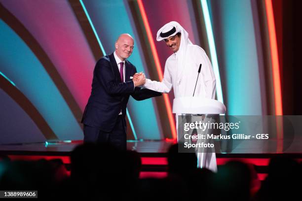 President Gianni Infantino shakes hands with Qatar's Emir Sheikh Tamim bin Hamad al-Thani on stage at Doha Exhibition Center on April 01, 2022 in...