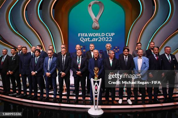 Managers of the competing teams pose for a photo alongside the Fifa World Cup Trophy during the FIFA World Cup Qatar 2022 Final Draw at the Doha...