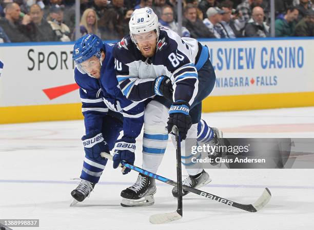 Pierre-Luc Dubois of the Winnipeg Jets battles for control of the puck against Alexander Kerfoot of the Toronto Maple Leafs during an NHL game at...