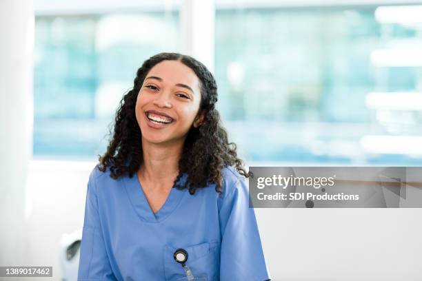 smiling, happy young adult nurse or physical therapist - one young woman only health hopeful stock pictures, royalty-free photos & images